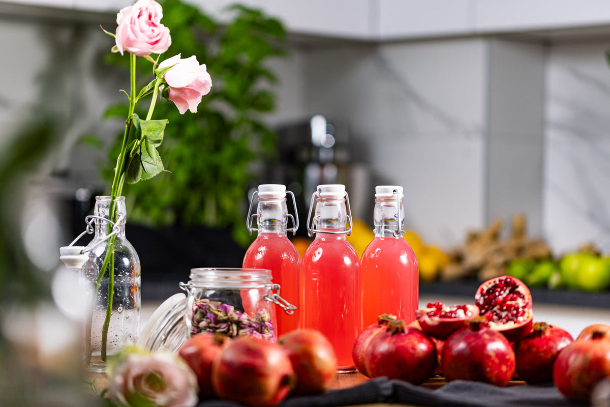 Ružičasta kombucha u bocama s kopčom, šipci, sušeni pupoljci ruže i ruža u vazi